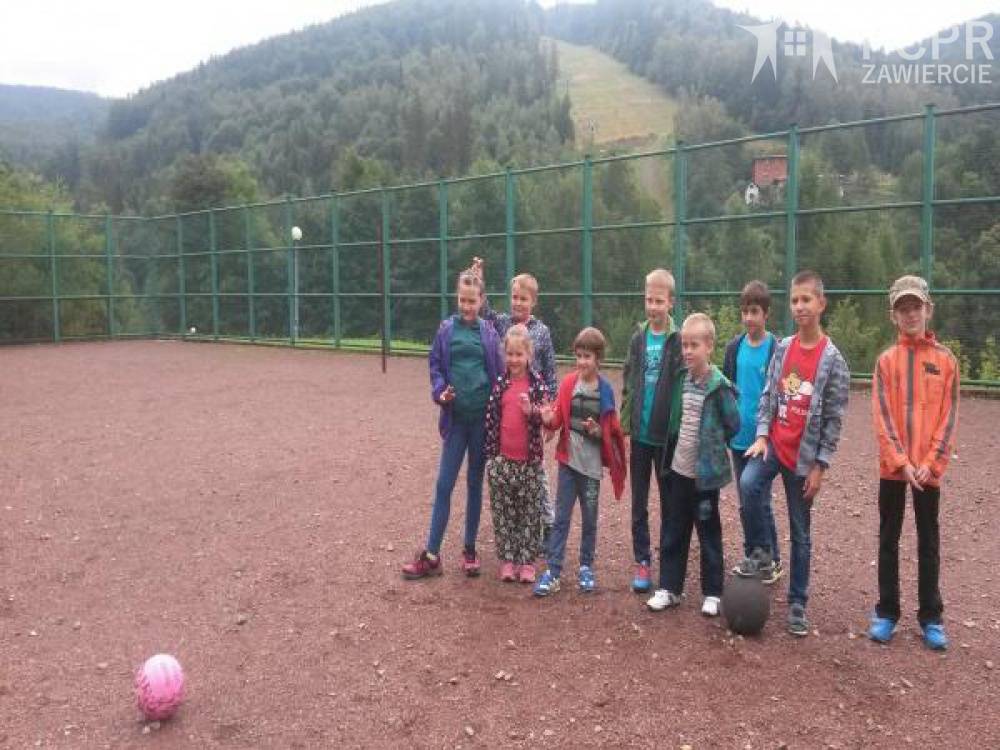 Zdjęcie: Grupa chłopców i dziewczynek stoi na boisku, a w tle stok narciarski